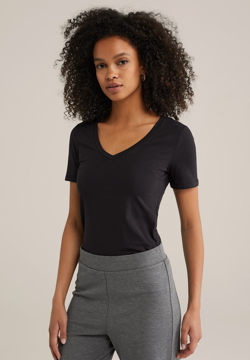 Sort kortærmet t-shirt med v-hals design, lavet af blødt stof, parret med grå højtaljede bukser. Simpelt og alsidigt outfit.