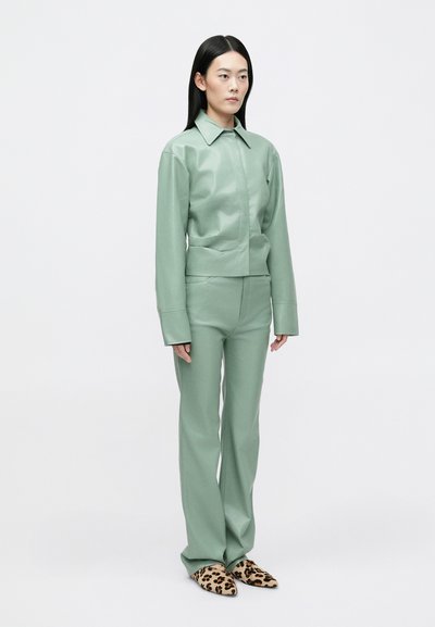 Conjunto de imitação de couro verde menta, composto por uma jaqueta ajustada com colarinho e mangas largas, combinada com calças a condizer e sapatos de padrão de leopardo.