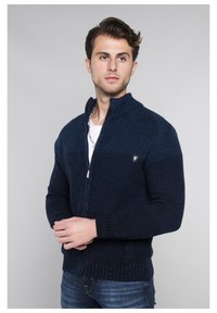 Marineblauer Strick-Reißverschluss-Pullover mit Stehkragen, gerippten Bündchen und Saum. Verfügt über ein kleines Emblem auf der Brust und strukturierten Stoff.