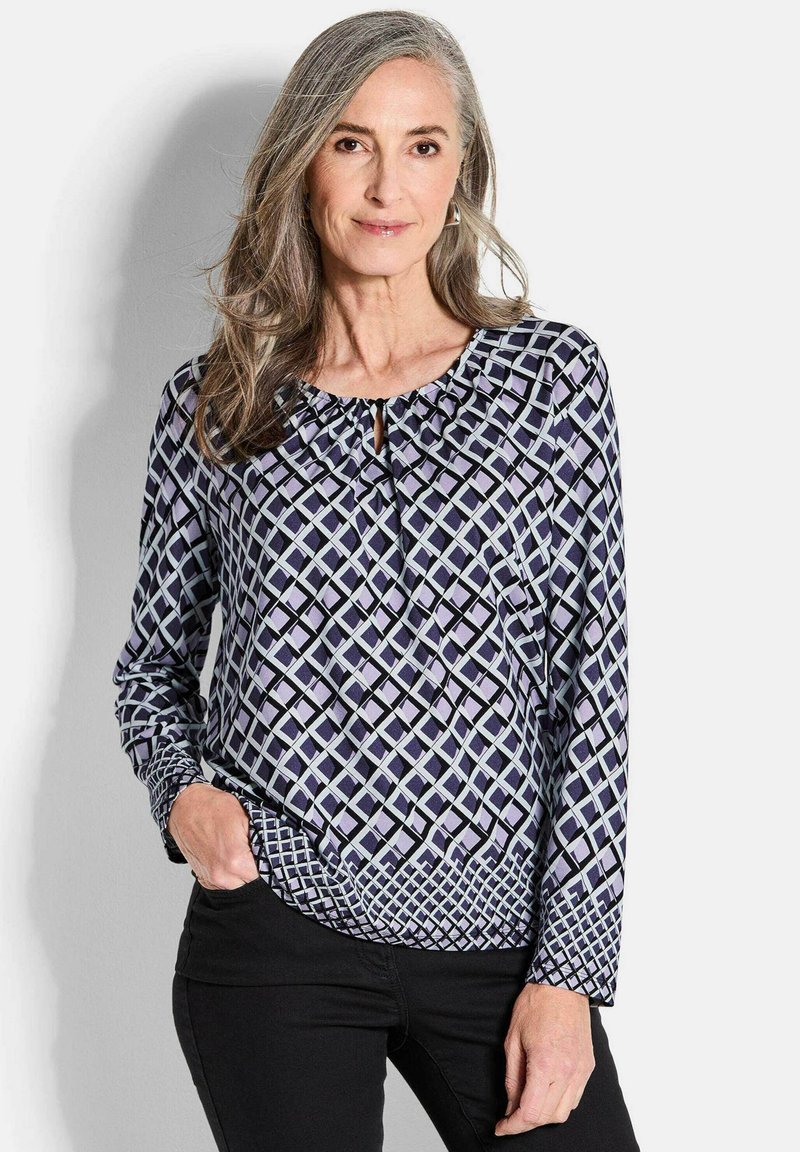 Langarmbluse in Marineblau und Helllila mit geometrischem Muster, Schlüssel-Detail am Ausschnitt und gerafftem Stoff am Kragen.