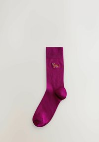 Chaussette magenta avec bord-côte et petit chien corgi brodé près du haut, posée à plat sur un fond clair.