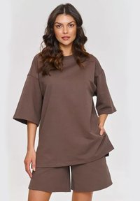 Brązowy, oversize t-shirty z krótkim rękawem, w połączeniu z pasującymi szortami do kolan. Miękka tkanina o luźnym kroju i bez widocznych wzorów.