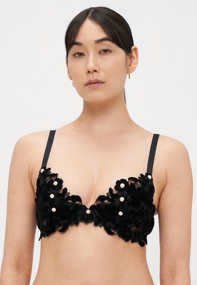 Črni čipkasti modrček z rožnim vezenjem, bisernimi dodatki in nastavljivimi trakovi. Dizajn je polprozoren z globokim izrezom.