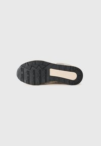 Suola di scarpe sportive in gomma nera, con battistrada testurizzato per una migliore aderenza e un'intersuola beige con accento di marca. Materiale resistente e design strutturato.