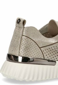 Zapatilla beige con un acabado texturizado y brillante, detalles perforados, un acento metálico plateado en la suela y una etiqueta de tela en el talón.