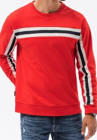 Sudadera roja de manga larga, con rayas horizontales blancas y azul marino en el pecho y en las mangas. Fabricada en algodón, de ajuste relajado.