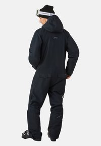 Zwarte waterdichte skipak in één stuk met capuchon, ritsen aan de benen en logo op de rug; heeft een gladde textuur en ergonomische pasvorm.