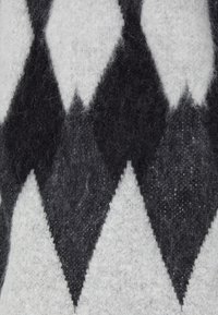 Svart och grå mönstrad tyg med diamantdesign. Texturen verkar mjuk och luddig, med olika nyanser i ett stickat eller filtmaterial.