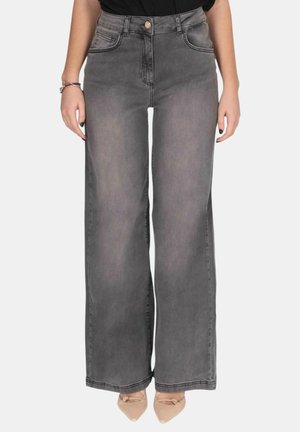 Jeans grigi a vita alta e gamba larga con tasche frontali e chiusura con bottoni, indossati con ballerine beige con punta appuntita e top nero.