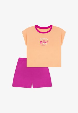 Pfirsichfarbenes Kurzarmshirt mit pinkem Saum und dem Schriftzug "Squeeze the Day", kombiniert mit leuchtend pinken Shorts.