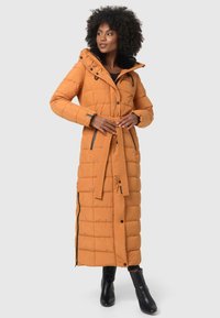 Doudoune orange moutarde avec capuche, motif matelassé vertical, accents noirs et ceinture à la taille. Présente une longueur longue et des zips sur les côtés.