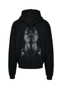 Svart huvtröja med en stor porträttmotiv i gråskala på ryggen, som detaljerar ansiktsdrag och ett kedjehalsband, med mjukt tyg. 