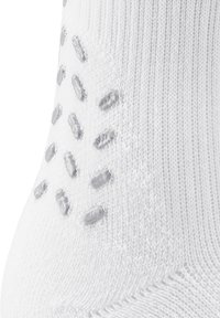 Calzino bianco con puntini in silicone testurizzati sulla superficie, realizzato in un morbido tessuto a maglia con design a coste.