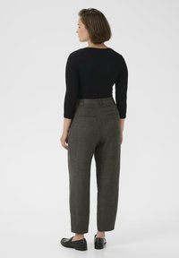 Black fitted long-sleeve top paired with textured, tapered gray trousers and black slip-on shoes, viewed from the back against a white background.