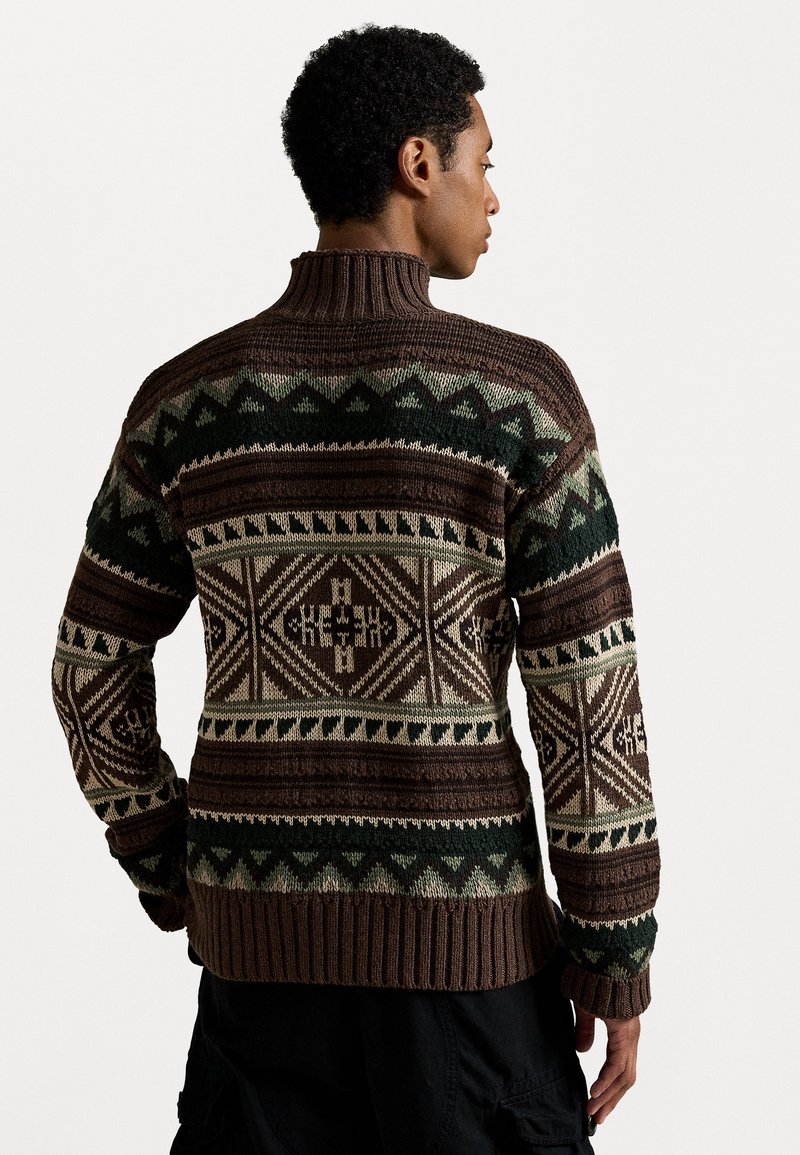 Brun stickad tröja med hög krage, med geometriska mönster i mörkgrön, kräm och brun. Ribbad ärm- och nederkant.