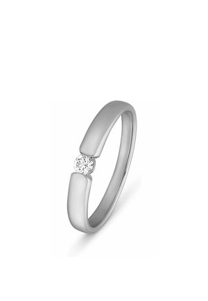 Silberner offener Bandring mit einem kleinen runden Diamanten, der zwischen den beiden Enden des Rings auf weißem Hintergrund eingefasst ist.