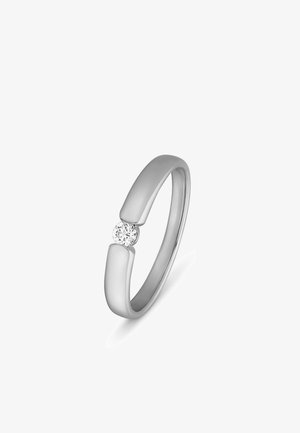 Silberner offener Bandring mit einem kleinen runden Diamanten, der zwischen den beiden Enden des Rings auf weißem Hintergrund eingefasst ist.