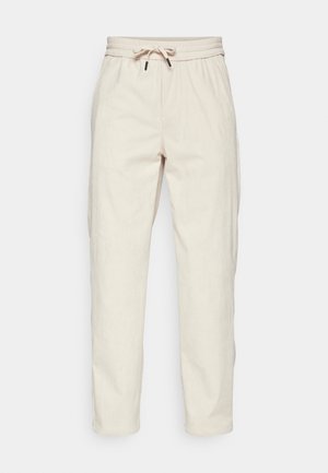 Light beige corduroy trousers with a drawstring waistband, side pockets, and a relaxed fit, featuring ribbed texture and tapered legs.
