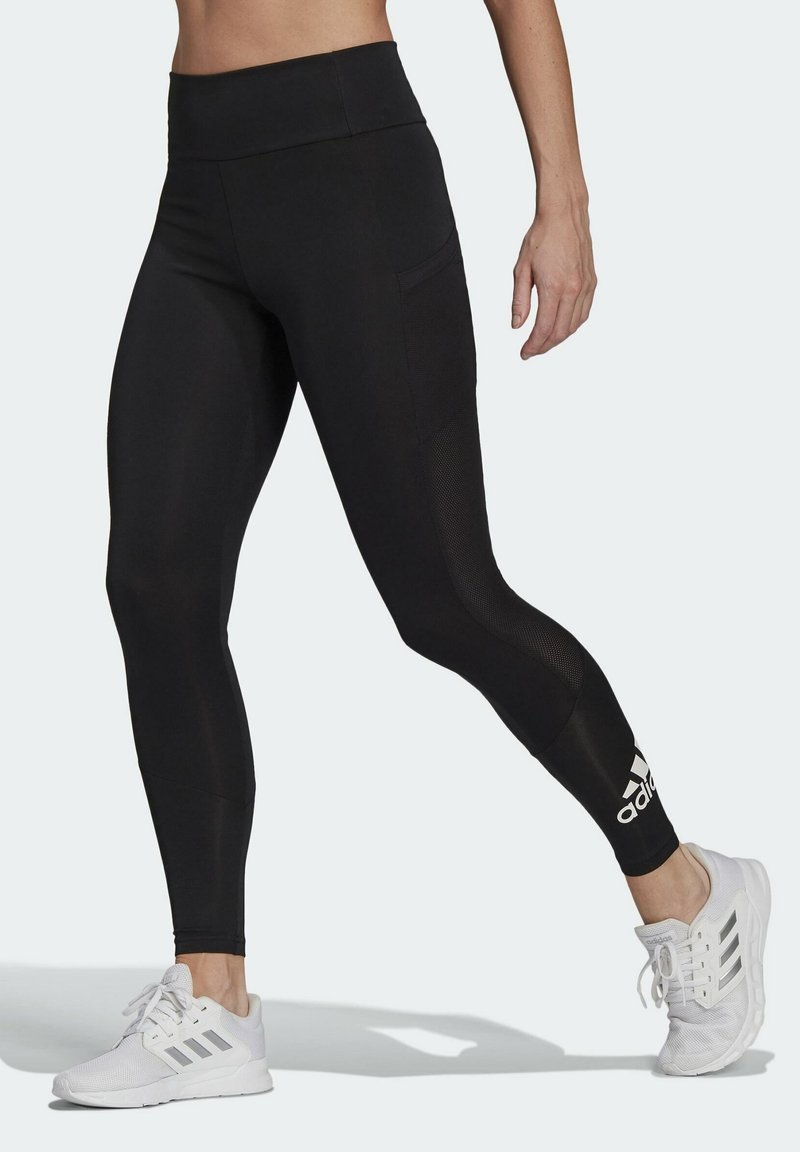 Czarne legginsy sportowe z wysokim stanem, z bocznymi panelami z siateczki dla lepszej wentylacji oraz białym logo Adidas na wysokości kostki.