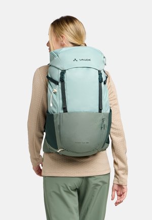 Zaino Vaude verde chiaro con spallacci regolabili, tasche esterne e design slanciato. Presenta una chiusura superiore e dettagli in rete.