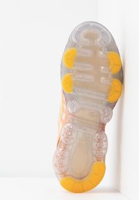 Sko sula med en genomskinlig design och orange och gula gummidetaljer, texturerat grepp och framträdande bubblor för stötdämpning.