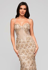 Beige Abendkleid mit einem enganliegenden Oberteil, verziert mit goldenen Pailletten und Fransen, dünnen Trägern und einem detaillierten Diamantmuster am Rock.