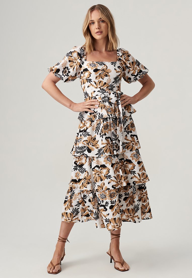 Floral dress in white with black and orange flowers, featuring short puff sleeves, a square neckline, and tiered ruffle hem.