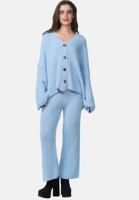 Ensemble de lounge en tricot côtelé bleu comprenant un pull surdimensionné à boutons avec un col en V et des manches larges, associé à un pantalon à jambes larges assorti.