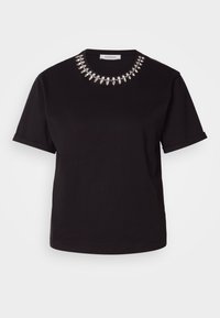 Chemise noire à manches courtes avec encolure ronde ornée d'une rangée de grosses perles argentées brillantes et de petits cristaux.