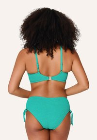 Set di bikini turchese con texture a costine, spalline regolabili e una chiusura in metallo dorato. Slip a vita alta con dettagli legati.