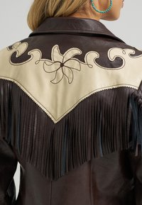 Smeđa kožna jakna s krem yoke dijelom ukrašenim cvjetnim vezom, resicama i crnim detaljima duž rubova.