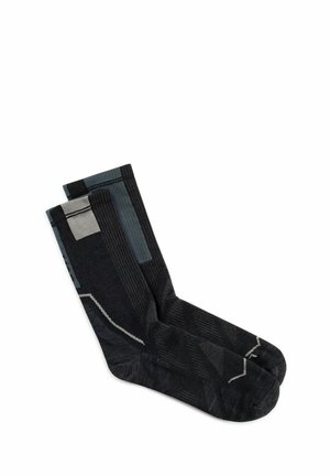 Par de calcetines negros tipo crew con patrones geométricos grises, colocados planos sobre un fondo blanco.