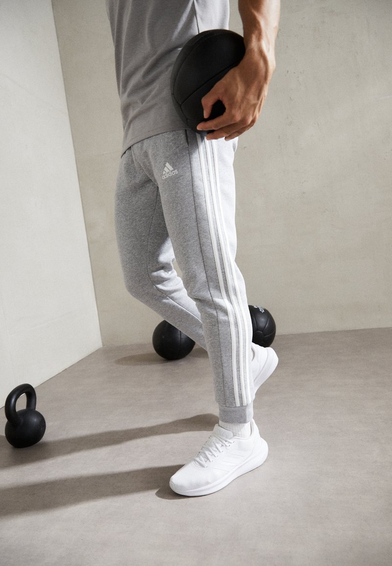 adidas Sportswear - ESSENTIALS TAPERED CUFF 3 STRIPES PANTS - Teplákové kalhoty - medium grey heather, Zvětšit