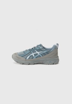 Bottine de sport bleu clair avec des accents gris, dotée d'une tige en mesh, d'une semelle en caoutchouc texturé et d'un renfort à la pointe pour une durabilité accrue.