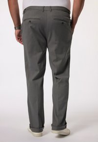 Graue Hose mit glatter Textur, ausgestattet mit mit Knöpfen gesicherten Gesäßtaschen und umgeschlagenen Säumen über weißen Sneakern.