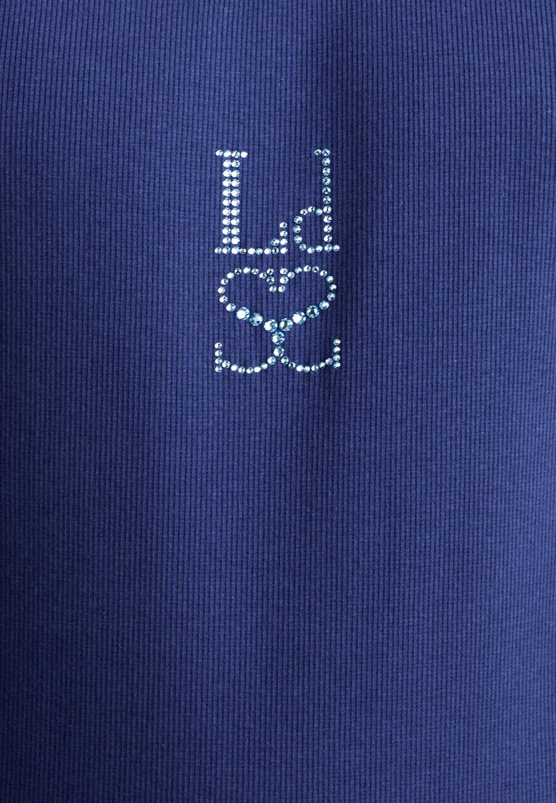 Marineblauer, gerippter Stoff mit den Buchstaben "Ld" und "Sc", verziert mit hellblauen Strasssteinen, zentriert über einer Herzform.