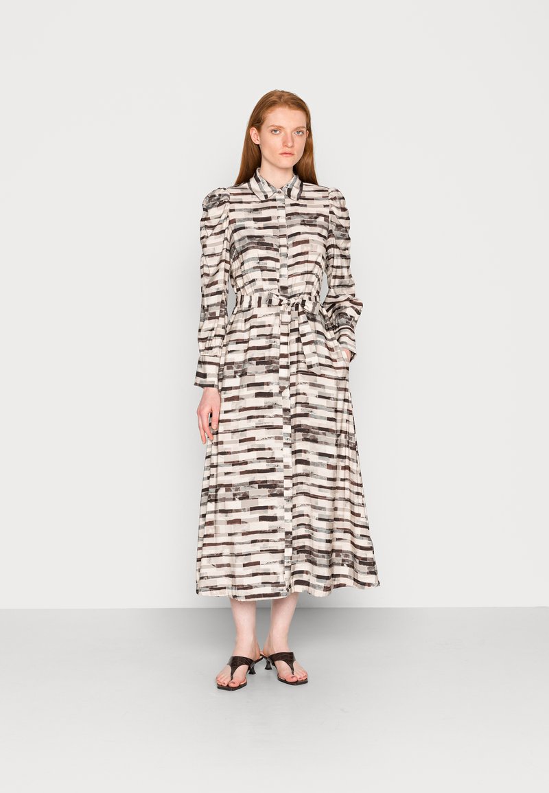 Vestido longo com um fecho de botões na frente, feito de um tecido leve e com um padrão riscado em preto, branco e bege, de forma abstrata e suave.