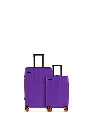 Dwie fioletowe walizki z twardą skorupą, z czarnymi wysuwanymi uchwytami i pomarańczowymi kółkami, stojące obok siebie na białym tle.
