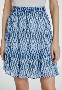 Jupe bleu à motifs avec un design en couches, dotée d'une taille smockée, d'une fermeture à cordon et d'accents décoratifs en perles.