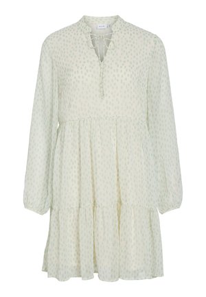 Rochie crem deschis cu mâneci lungi, cu buline verzi subtile, fustă stratificată, decolteu în V și închidere cu fundă în față la gât.