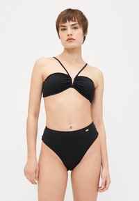 Black bikini set featuring a ribbed texture, with a bandeau top and high-waisted bottoms. Adjustable straps and subtle gold hardware detail.