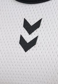 Zwei schwarze, nach unten zeigende Chevron-Zeichen auf weißem, atmungsaktivem Netzgewebe mit schwarzem Rand oben.