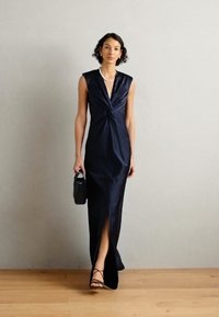 Merin öökleit tumesinisest satiinist keeratud bodiciga, sügava V-kaelusega ja reie kõrge lõhikuga. Kombineeritud väikese musta käekoti ja rihmadega sandaalidega.