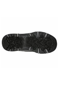 Suela de zapato deportivo negro con un patrón de relieve resistente, superficie de goma texturizada y logo de la marca con prominentes tacos de tracción.