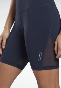 Mörkblå idrottsshorts med ett strukturerat midjeband, nätpaneler på sidorna och kontrasterande sömmar. Vit logotyp på benet.