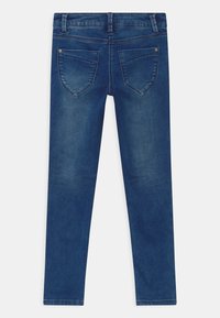 Jeans di denim blu skinny con due tasche posteriori, passanti per cintura e una texture liscia senza abrasioni o decorazioni visibili.