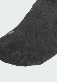 Schwarze Socke mit geripptem Muster, ausgestattet mit verstärkter Zehenpartie. Der Stoff wirkt elastisch und robust, entworfen für Komfort und Passform.