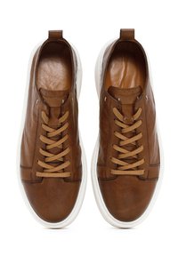 Baskets en cuir marron avec une texture lisse, dotées de lacets beiges, d'une semelle en caoutchouc blanche et d'un design minimaliste.