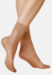 Beige, durchsichtige Knöchelsocken mit elastischen Bändern oben, mit dem dezent aufgedruckten Markennamen "KUNERT". Weiche Textur und Passform.