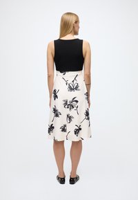 Juodas be rankovių viršus su prigludusia liemene, pereinantis į kremine spalva puoštą sijoną su juodos spalvos gėlių raštais. Lygus paviršius, sijono ilgis iki kelių.